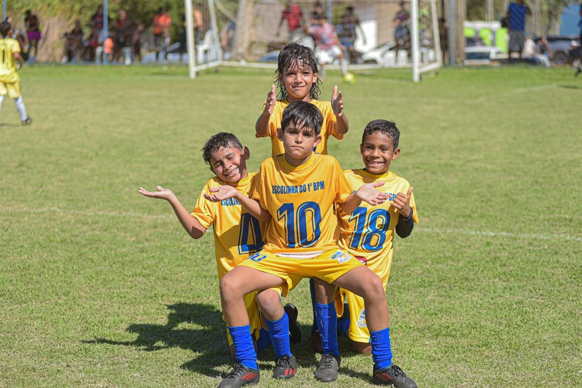Atletas da Escolinha do 1º BPM comemorando o gol em campo